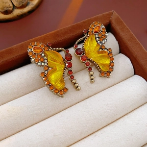 Detail of vintage butterfly earrings with yellow enamel and sparkling orange rhinestones