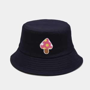 Detailed close-up of pink mushroom embroidery on a navy cotton bucket hat with clean stitching