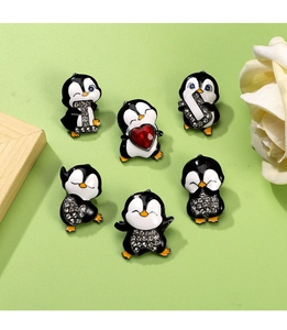 Detailed view of six cute penguin brooches with rhinestones and a red heart crystal