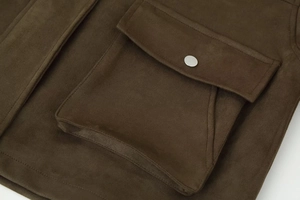 Detailed close-up of brown suede pilot jacket featuring a large flap pocket and silver snap button