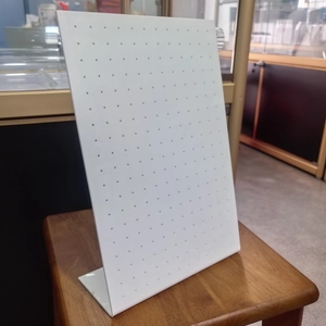 Detailed view of white L-shaped acrylic jewelry stand with multiple holes for earrings