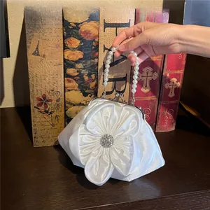 Close-up of white satin evening bag with large fabric flower and pearl handle