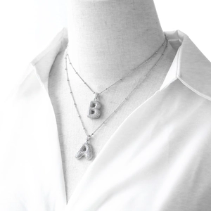 Detail of silver double layered chain with bubble style A and B letter pendants on mannequin