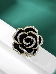Close-up of a vintage black camellia brooch with gold edges and sparkling crystals