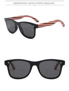 Macro shot of polished black sunglasses frame with red textured wood temples and rivets