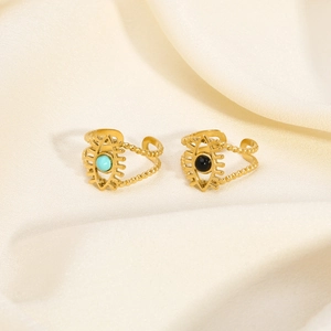 Detail of gold-plated evil eye rings with turquoise and black stones on silk fabric