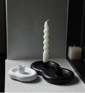 Detail of minimalist ceramic cloud candle holders in matte black and white finishes