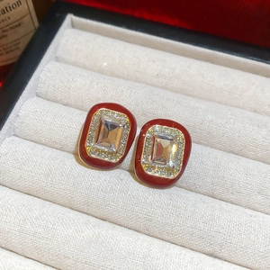 Macro shot of red enamel geometric earrings with crystal inlay on beige velvet pad