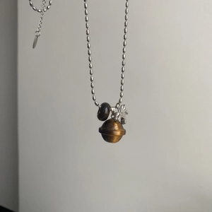 Close-up of tiger eye stone sphere and silver pony charm on a boutique necklace