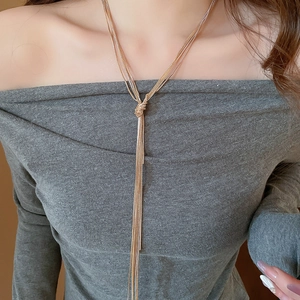 Detail of a multi-layer golden knot chain necklace with elegant long tassels for women