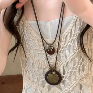 Detail of vintage layered necklace featuring wooden disk and bronze bow knot pendant