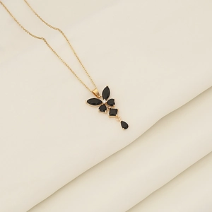 Detailed close-up of gold butterfly pendant with black gemstone tassels on fabric