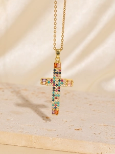 Detail view of a gold cross pendant necklace featuring multi-colored zircon stones