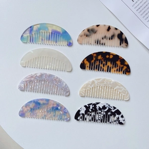 Flat lay of small marble-patterned acetate hair combs in various colors and textures