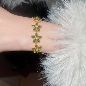 Detailed view of rose gold bracelet with olive green crystal flowers on wrist