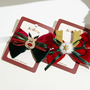 Detail of Christmas bow hair clips featuring velvet ribbon with reindeer and bell charms