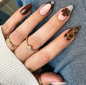Almond press-on nails with brown leopard print and dark floral patterns on a hand