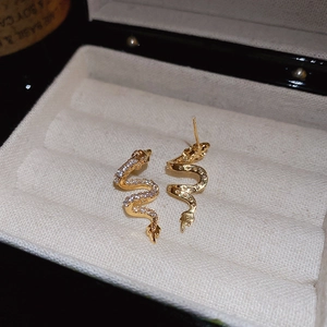 Detailed view of gold snake earrings with white cubic zirconia in a jewelry box