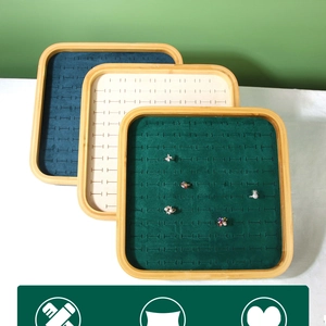Detail of bamboo jewelry trays with green, beige, and blue velvet slots for rings