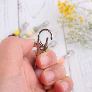 Hand holding a macaron silicone bead bracelet with metal clasp and daisy keychain charm