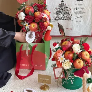 Christmas flower box with red apples, roses, and festive Merry Christmas gift bag