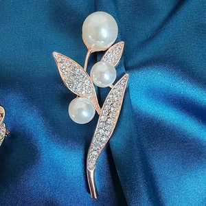 Detail of rose gold flower brooch with white pearls and sparkling crystal leaves
