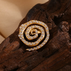 Macro detail of 18K gold-plated swirl brooch with white rhinestones on rustic wood