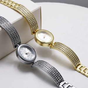 Detailed view of silver and gold oval watches with crystal-embellished metal bracelets