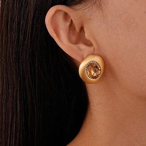 Detail eines goldenen Vintage-Ohrrings mit bernsteinfarbenem Stein und Strassbesatz