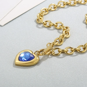 Gros plan d'un collier chaîne à fermoir OT doré avec pendentif cœur en cristal bleu