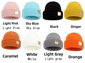 Close-up of winter knit beanies in eight colors with golden smiley face patches