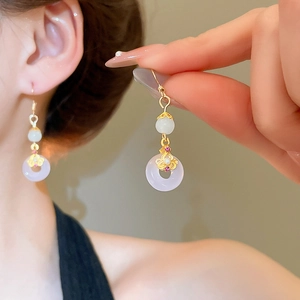Détail de boucle d'oreille en calcédoine lavande avec fleur dorée et perle blanche