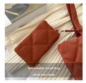 Detail view of brick red quilted small pouch with high-quality gold metal zipper and hook