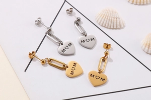 Detailed macro view of gold and silver MOM heart earrings on a white background