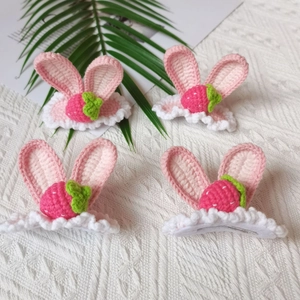 Detail of four handmade pink crochet rabbit ear hair clips with strawberry accents