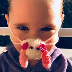 Close-up of handmade crochet sheep nose warmer with pink details and red ribbon rose
