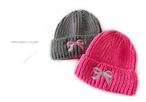 Close-up of grey and rose red knitted hats with bright pink bow embroidery detail