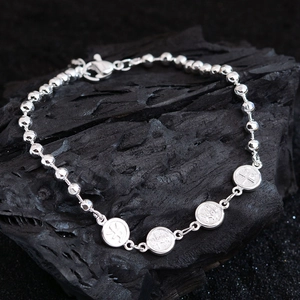 Minimalist silver beaded bracelet with embossed coin pendants on dark stone