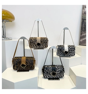 Detail of leopard print shoulder bags with elegant square buckles on minimalist displays