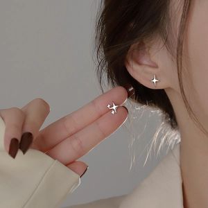 Minimalist silver four-point star stud earrings shown on model for size and delicate style