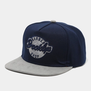 Detail of Brooklyn Barber Shop embroidery on flat brim snapback hat with suede peak