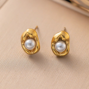 Macro view of golden heart-shaped earrings with pearls and modern lava texture