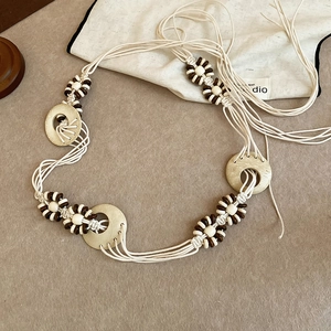 Detailed view of hand-woven cotton rope belt with geometric wooden rings and dark brown beads