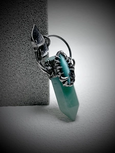 Detailed view of green crystal hexagonal pendant held by vintage silver claw with leaf motifs