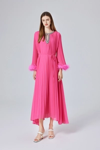 Détail d'une robe longue plissée rose fuchsia avec poignets en plumes et col à sequins