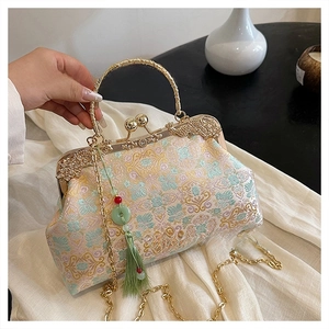 Close-up of vintage floral brocade bag with golden carved handle and green tassel