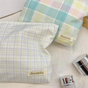 Detail of fresh plaid cosmetic bags with fabric label on a white linen surface