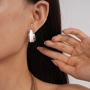 Macro shot of a 18k gold-plated C-shaped double-layer hoop earring with white enamel