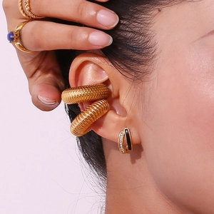 Detail of 18K gold-plated U-shape cross earrings with black enamel and rhinestones on ear