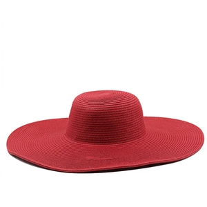 Detail of red wide-brim straw hat showing the intricate woven texture and round sun-cap top